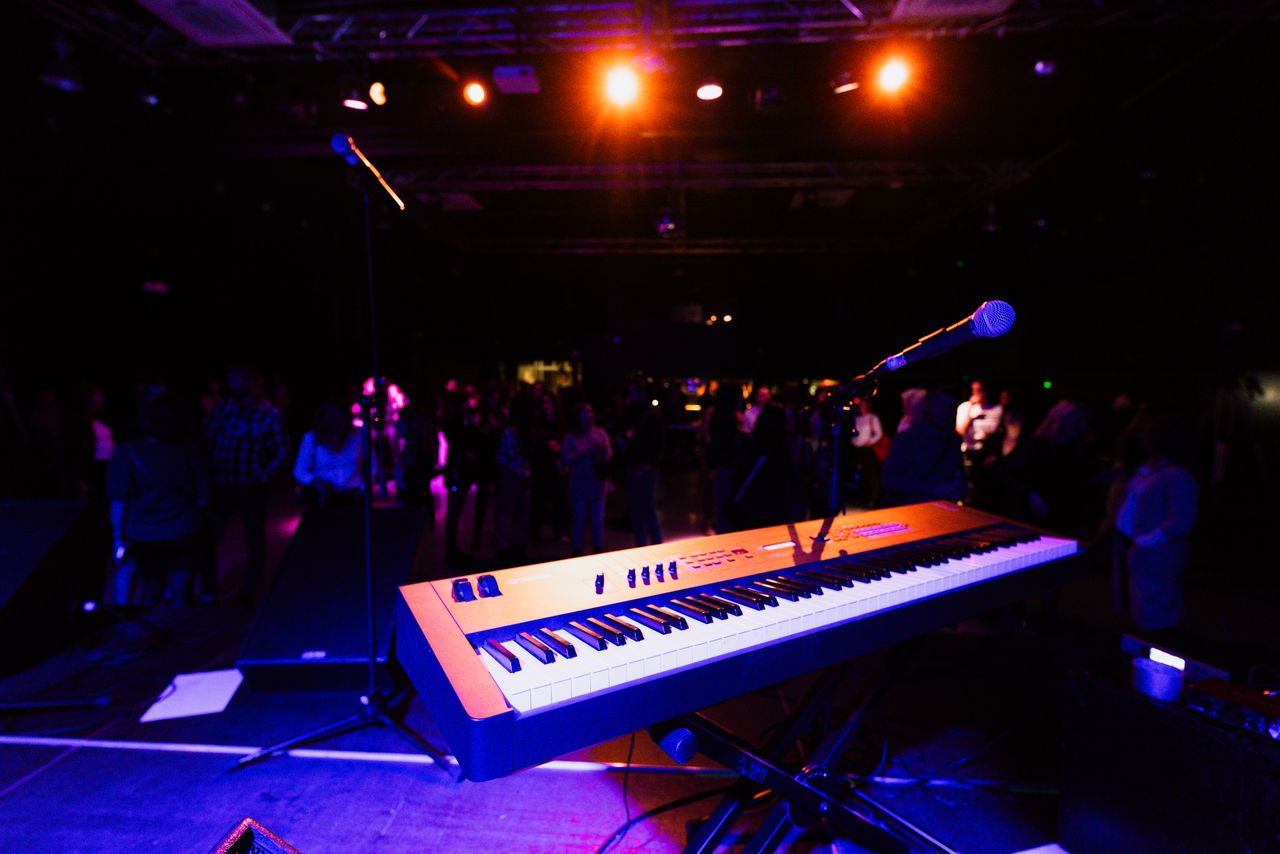 A vibrant nightclub scene with a keyboard and microphone on stage, ready for a live performance.