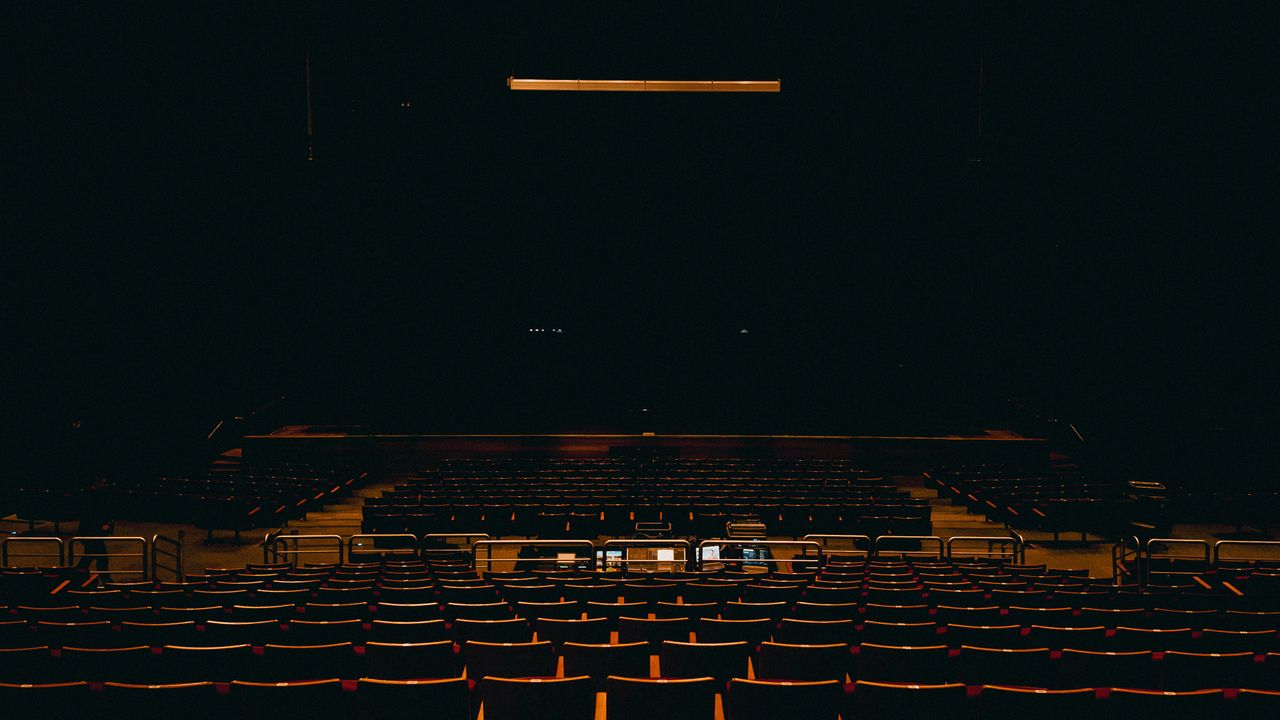 A dark and empty auditorium in Fortaleza, featuring rows of chairs and a stage.