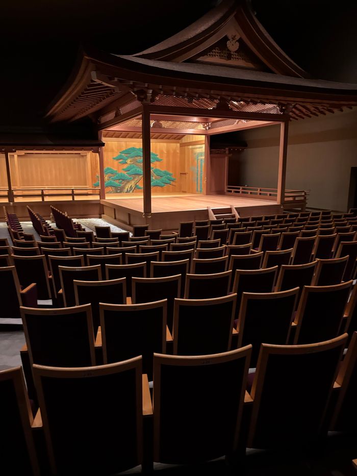 Interior view of a traditional Japanese Noh theatre with empty seating and stage.